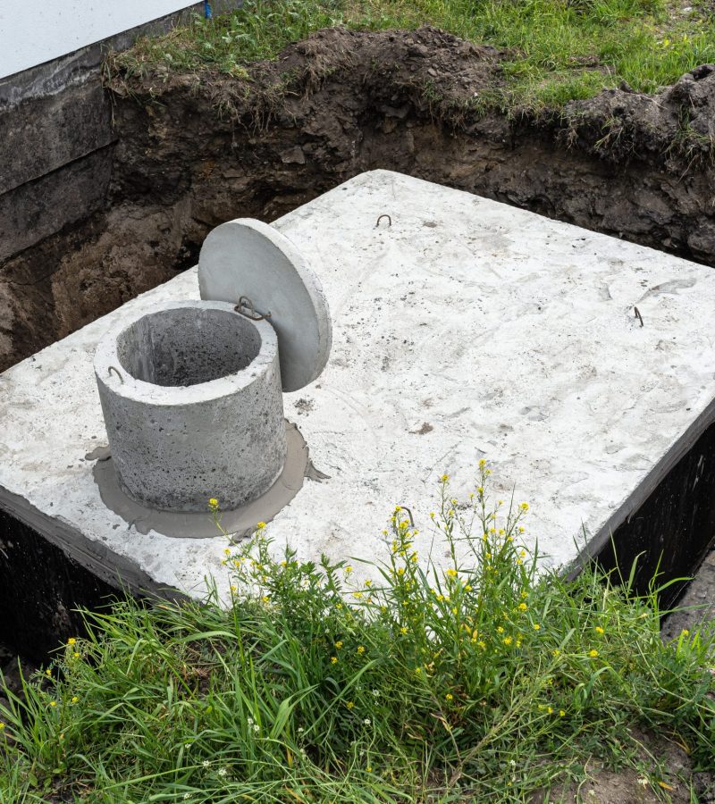 Concrete septic tank with a capacity of 10 cubic meters placed in the garden by the house, visible water below.