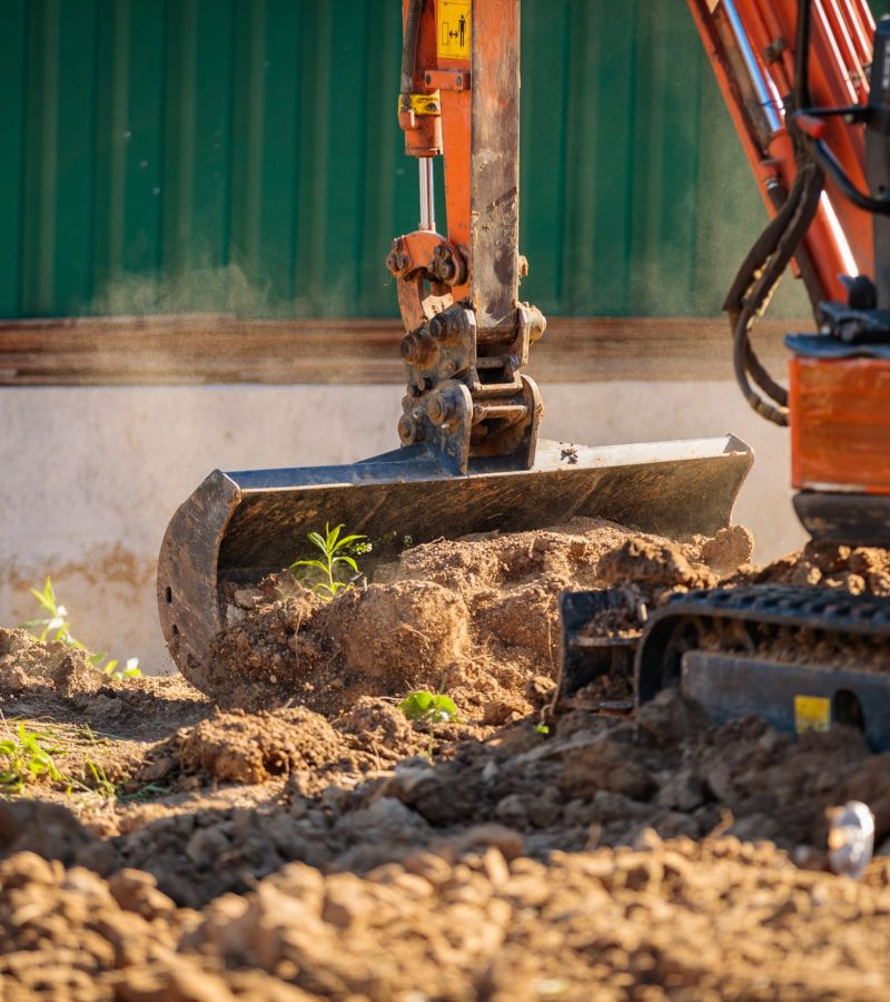 A minitractor rakes the earth with a bucket. Land works